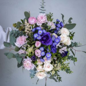 Runsas ja viileän sävyinen Huurteinen-kukkakimppu, jossa on liiloja vuokkoja, vaaleanpunaisia ruusuja ja eukalyptusta.