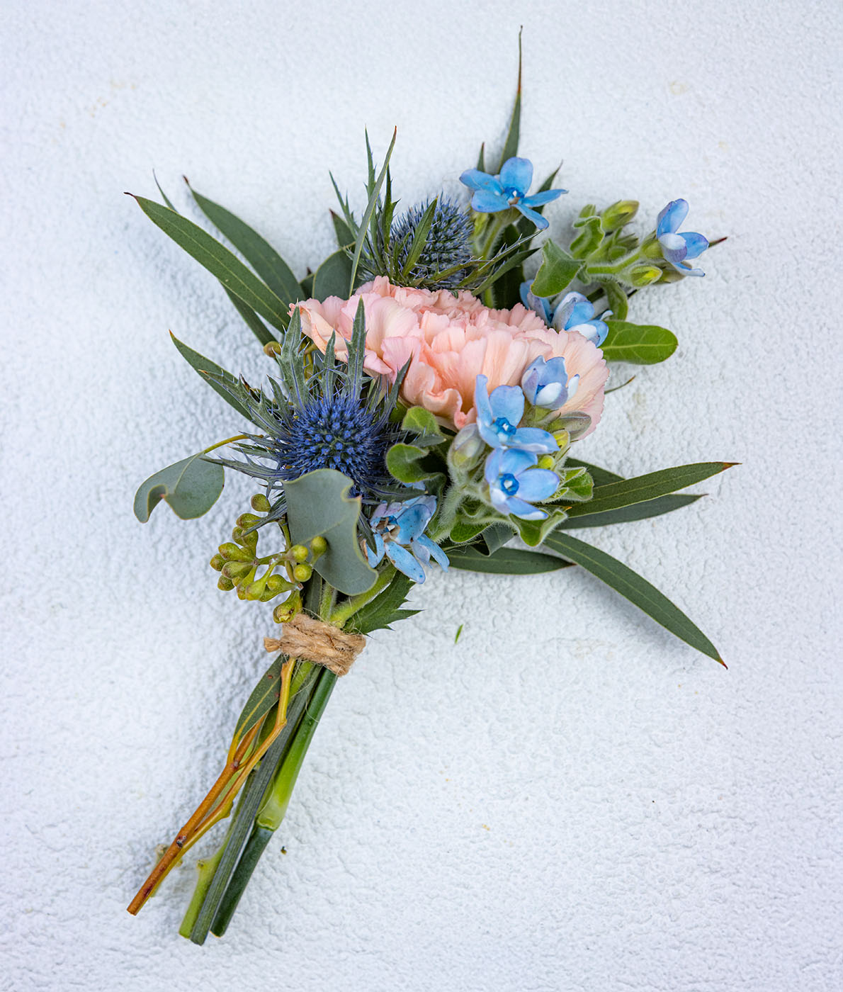 Käsityönä tehty kukkaviehe jossa persikka neilikka ja sininen piikkiputki