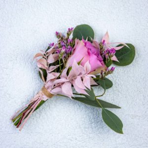 Vaaleanpunainen ruusu kukkavieheenä lilaa ikikukkaa ja eukalyptusta taustallaan